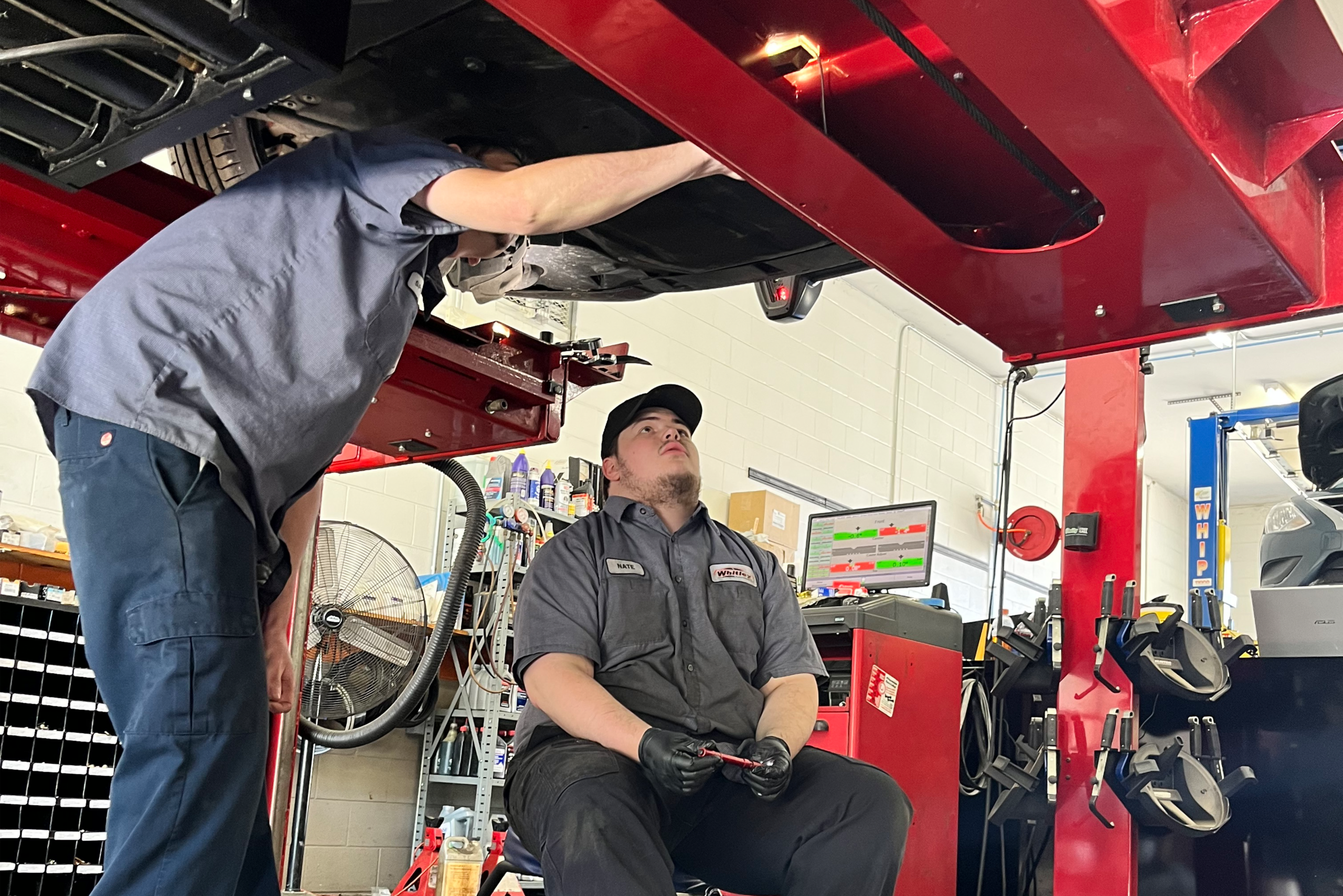 Technicians looking at the underside of a vehicle.