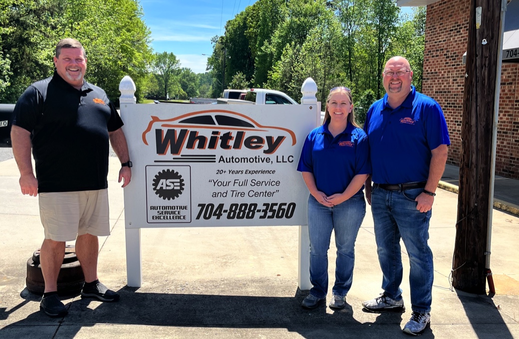 Whitley Automotive owners Chad and Tassa Whitley, along with Manager Gary Hastings standing beside the Whitley Automotive shop sign outside of shop.