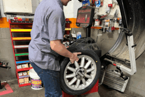 tire services, auto repair in Locust, NC at Whitley Automotive. Image of a technician positioning a wheel on a balancing machine to ensure smooth, safe vehicle performance.