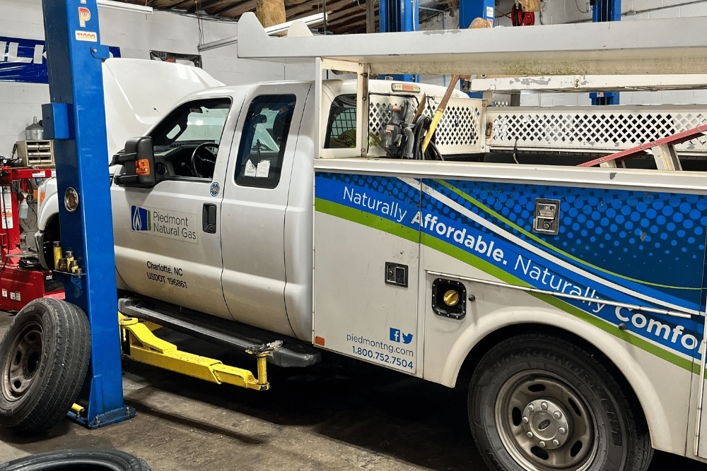 Emergency fleet services in Locust, NC by Whitley Automotive. Image of a Piedmont Natural Gas utility truck on a lift with hood open for service.