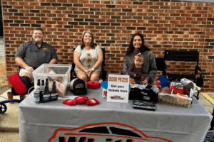 Whitley Automotive team welcomes visitors at their Community Open House event in Locust, NC, with a table of door prizes and giveaways.
