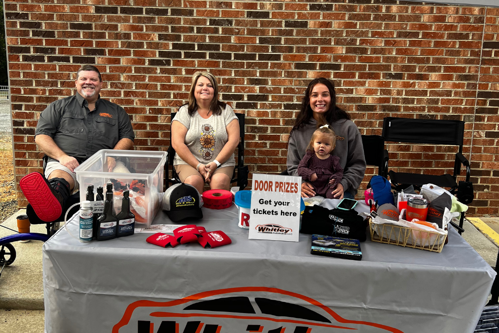 Whitley Automotive team welcomes visitors at their Community Open House event in Locust, NC, with a table of door prizes and giveaways.