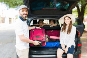 Car Maintenance Checklist in Locust, NC by Whitley Automotive. Image of a family loading luggage into the back of an SUV, highlighting safe and reliable vehicle readiness for long-distance travel.