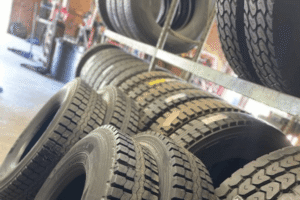 Tire replacement, auto repair in Locust, NC by Whitley Automotive. Image of multiple new all-season and truck tires stacked and displayed inside the shop, ready for installation and replacement to improve traction and safety.